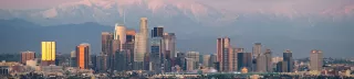 A distant, panoramic view of the Los Angeles skyline, with mountains in the background.