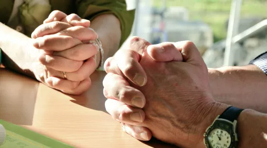 Two pairs of hands folded in prayer.