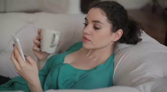 Woman holding a mug and cell phone.
