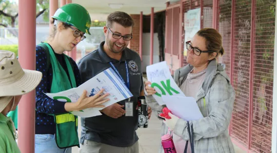 Three people review a plan during an earthquake drill 