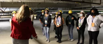Young women in hard hats looking at the underground basement of a building.