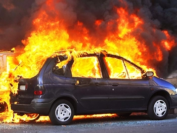 Photo of a car on fire, in a row with other cars after exploding