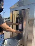 Photo of a person filling an empty water bottle from a LA DWP free hydration station at a Metro train station.